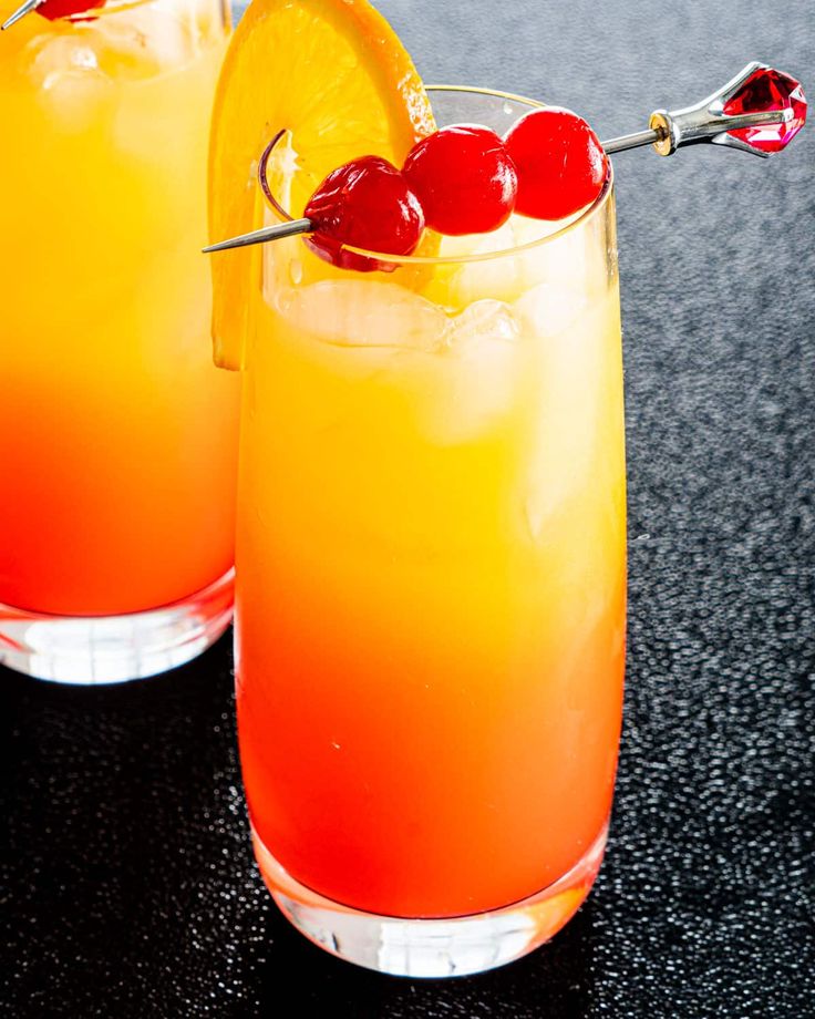 two glasses with tequila sunrise garnished with orange and ...